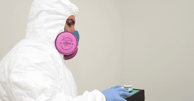 Inspector in PPE and a respirator preparing an air sampling cassette