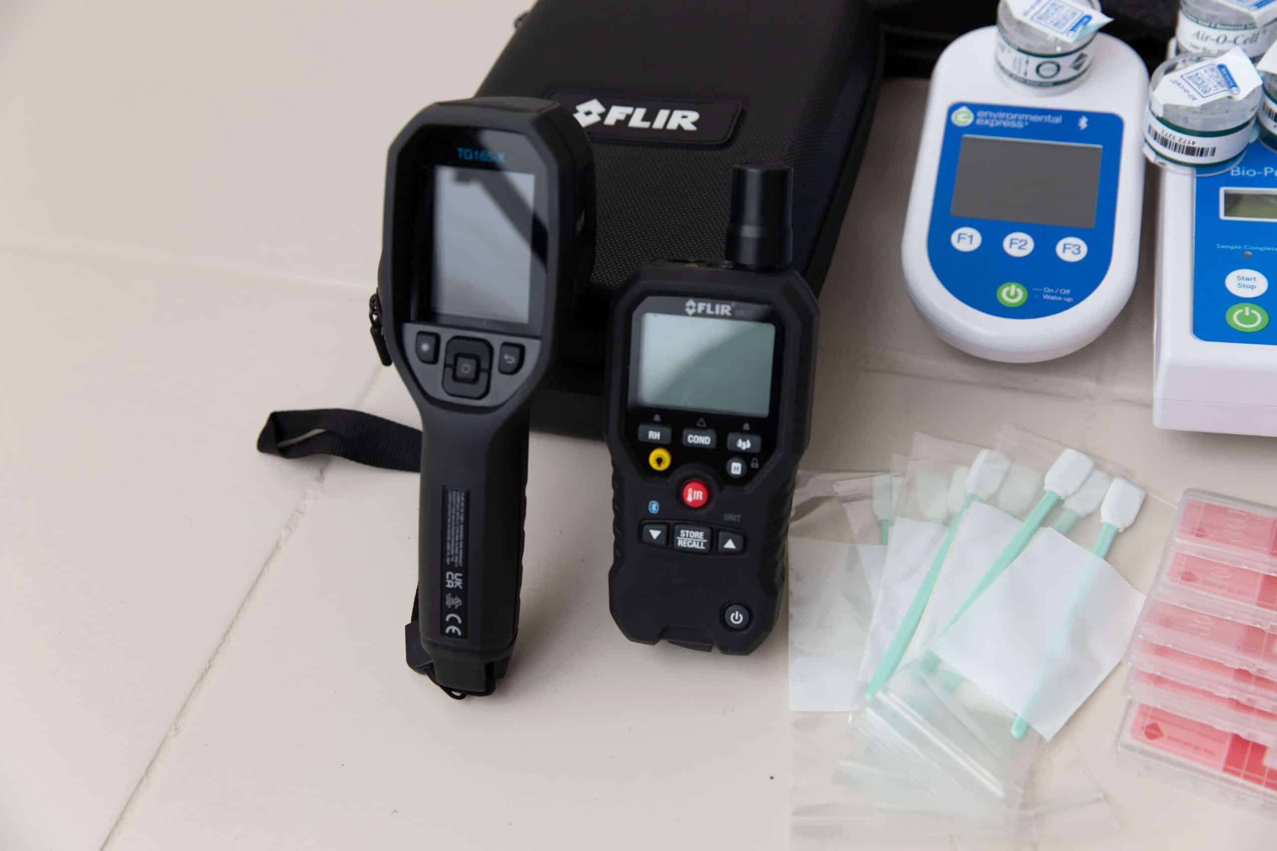 Thermal imaging camera and moisture meter beside sample swabs and vials