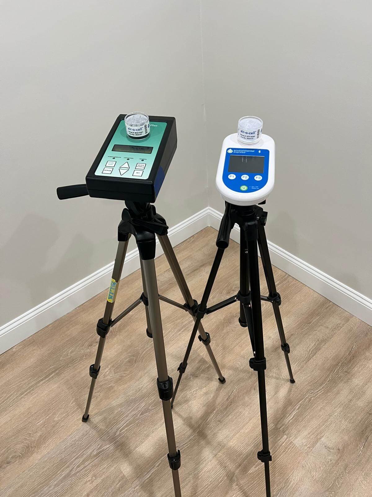 Two sampling pumps mounted on tripods on a hardwood floor